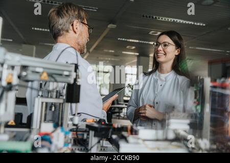 Male and female scientists discussing while standing by machinery in laboratory Stock Photo