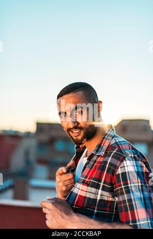 Smiling man gesturing while standing on rooftop in city
