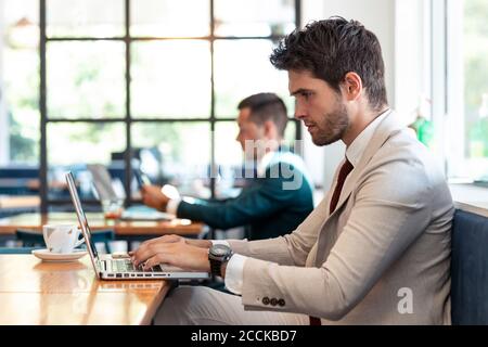 Serious businessman using laptop at table in cafe Stock Photo
