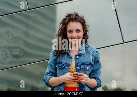 Young woman using smartphone at wall Stock Photo
