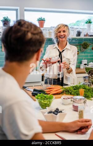 Cheerful female chef pouring juice in glass while teaching at cooking school Stock Photo