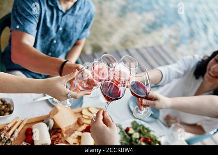 Friends having dinner at a lake clinking wine glasses Stock Photo
