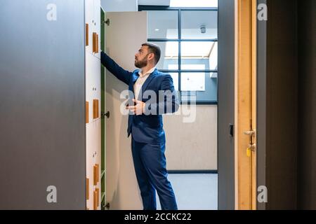 Bearded businessman searching something in locker room