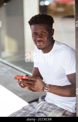 Close-up of young man using smart phone while sitting outdoors Stock Photo