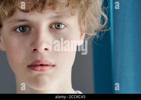 close-up portrait of redhead freckled teenager boy with bewitching look, caucasian boy with green eyes confidently looks at camera Stock Photo