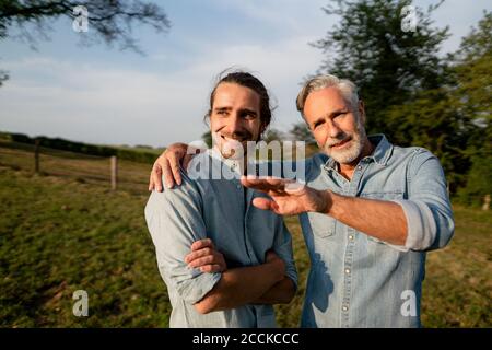 Mature father talking to adult son on a meadow in the countryside Stock Photo
