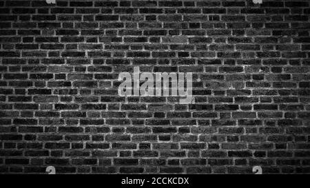 A panoramic view of an aged black brick wall texture with vignette. Stock Photo