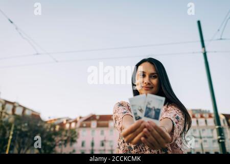 Young woman showing photographs of her in city Stock Photo