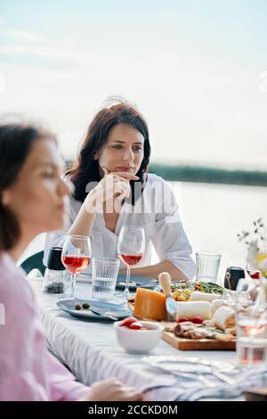 Young woman having dinner with friends at the lakeside Stock Photo