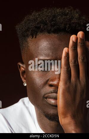 Close-up of young man covering face with hand Stock Photo
