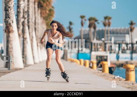 Young woman inline skating on promenade at the coast Stock Photo