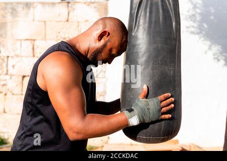 Bald mature man holding punching bag while standing in yard Stock Photo