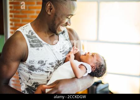 Close-up of happy father carrying baby daughter while standing at home Stock Photo