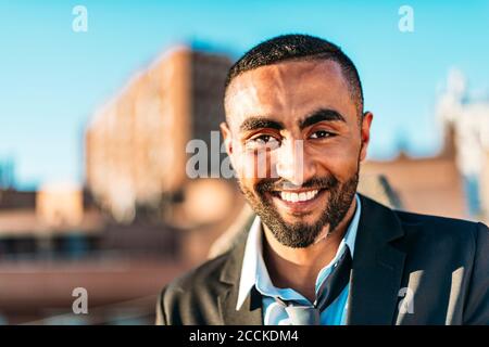 Handsome male entrepreneur smiling at rooftop Stock Photo