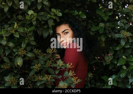 Portrait of young black-haired woman between leaves Stock Photo