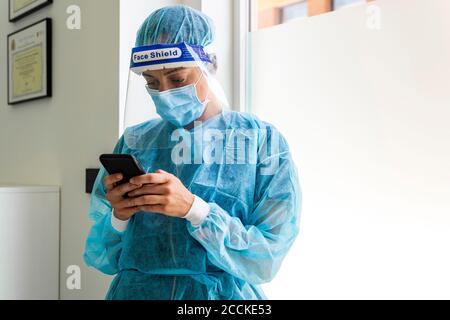 Female dentist texting through smart phone in clinic Stock Photo