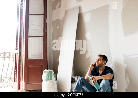 Worker on the phone having a break in a house under construction Stock Photo