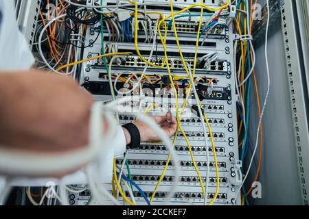 Close-up of mature man hand plugging cable in data center rack Stock Photo