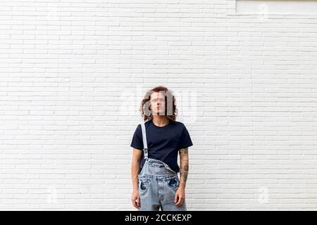 Young man standing against brick wall Stock Photo
