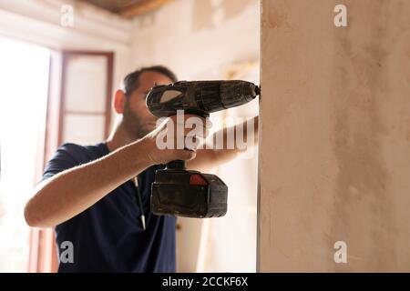 Construction worker using drill at a wall Stock Photo