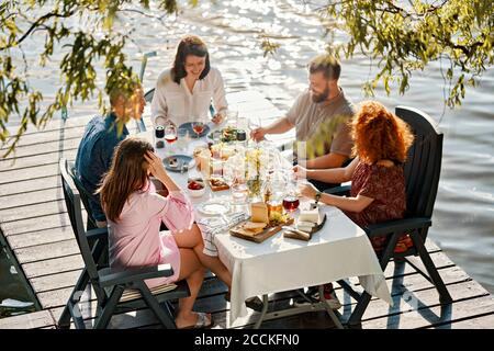 Friends having dinner on jetty at a lake Stock Photo