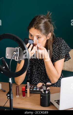 Young woman making a makeup video tutorial applying mascara Stock Photo
