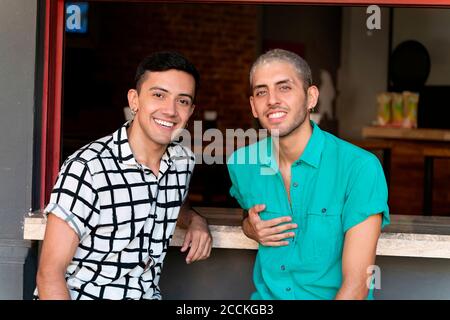 Friends smiling while sitting at bar counter of restaurant Stock Photo