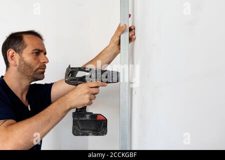 Construction worker using drill at a wall Stock Photo