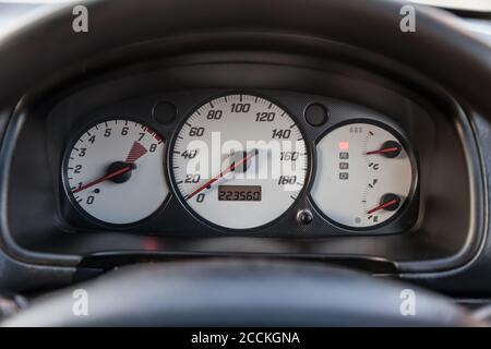 Car dashboard with white dials and red arrows on the speedometer, tachometer and other vehicle health gauges in a modern style on a black isolated bac Stock Photo