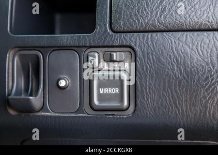 Control buttons for rear-view mirrors adjustment system, folding, a hole for coins for a parking machine in the passenger compartment in black. Stock Photo