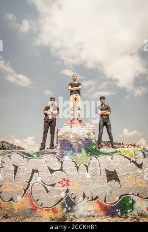 Teenage friends standing on a graffiti wall in an old run down industrial area Stock Photo