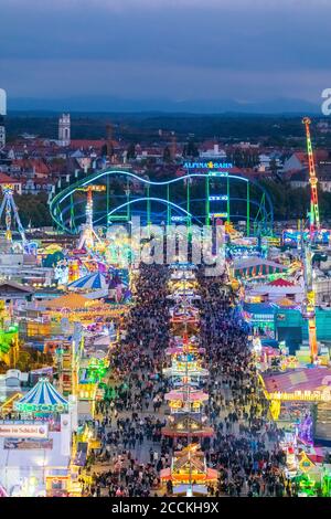 Germany, Bavaria, Munich, Drone view of crowds of people celebrating Oktoberfest in vast amusement park at dusk Stock Photo