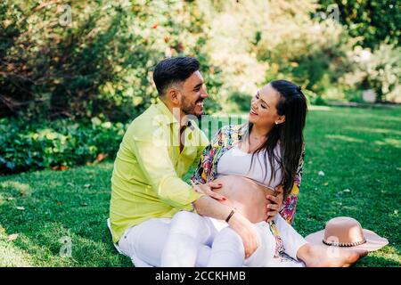 Cheerful man and pregnant woman spending leisure time together in park Stock Photo