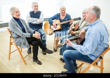 Seniors in retirement home attending guitar class, making music Stock Photo