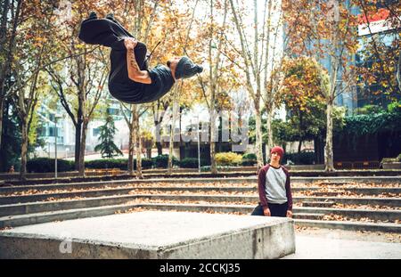 Young man jumping while friend looking in public park Stock Photo