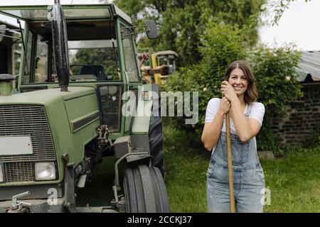 Portrait of a confident young woman standing at a tractor in the countryside Stock Photo