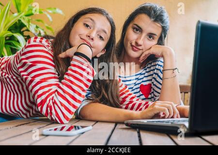 Sisters using laptop on table at home Stock Photo