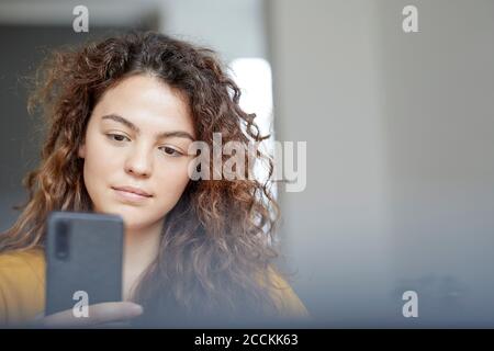 Beautiful young woman using mobile phone at home Stock Photo