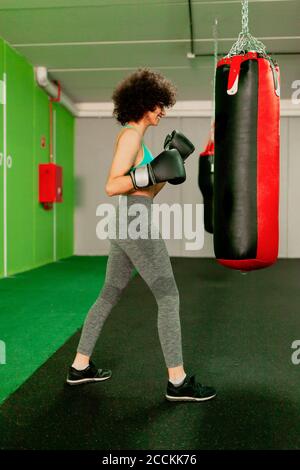 Female boxer practicing with punching bag in health club Stock Photo