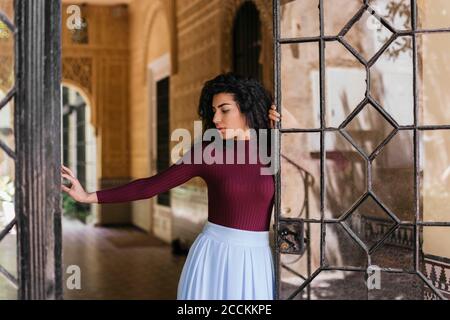 Portrait of young black-haired woman opening door Stock Photo
