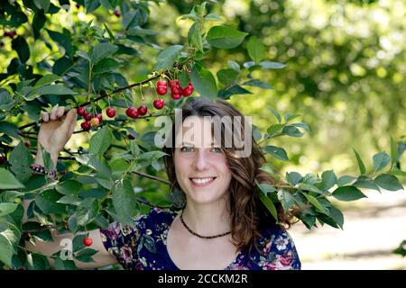 Close-up of smiling young woman holding cherry plant in farm Stock Photo