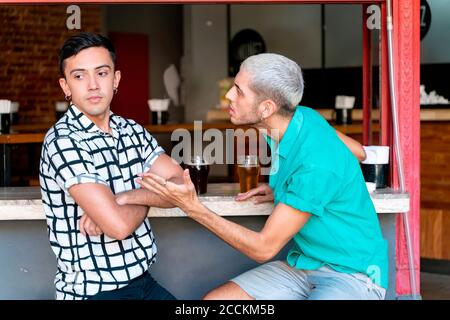 Gay couple arguing while sitting at bar counter Stock Photo