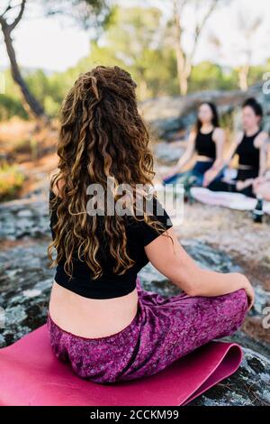 Yoga instructor practicing concentration with females in forest Stock Photo