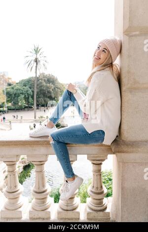 Young smiling woman sitting on balustrade enjoying view Stock Photo