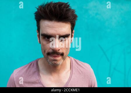 Close-up of mid adult man against blue wall Stock Photo
