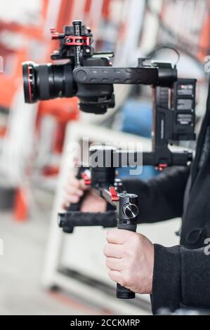 Videographer using stadicam, making video of machine at factory. Close up Stock Photo