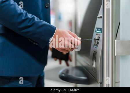 Close-up of businessman withdrawing money at an ATM Stock Photo