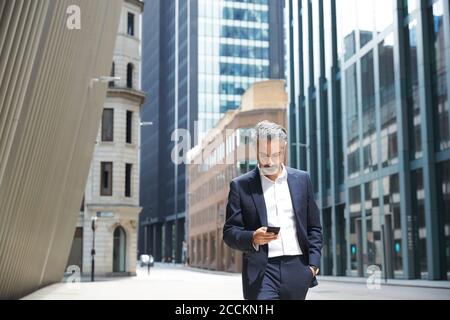 Businessman texting through mobile phone in city Stock Photo