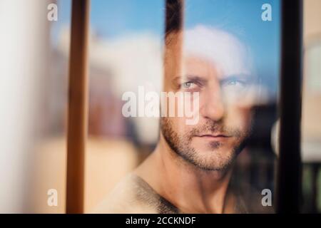 Close-up of thoughtful man looking through window seen through glass Stock Photo