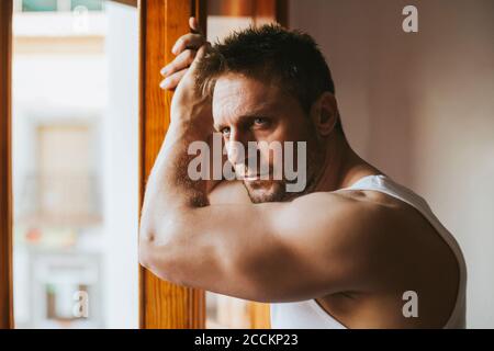 Close-up of serious thoughtful man looking through window at home Stock Photo